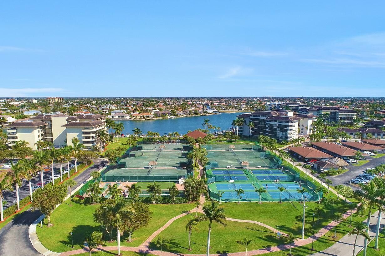 A resort with multiple tennis courts, a marina, and a view of the surrounding cityscape.