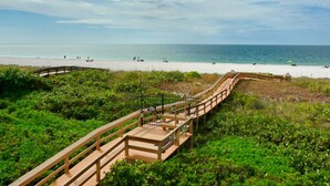 A wooden boardwalk leading to a beach with clear skies.