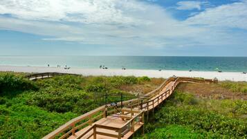 A wooden boardwalk leading to a beach with clear skies.