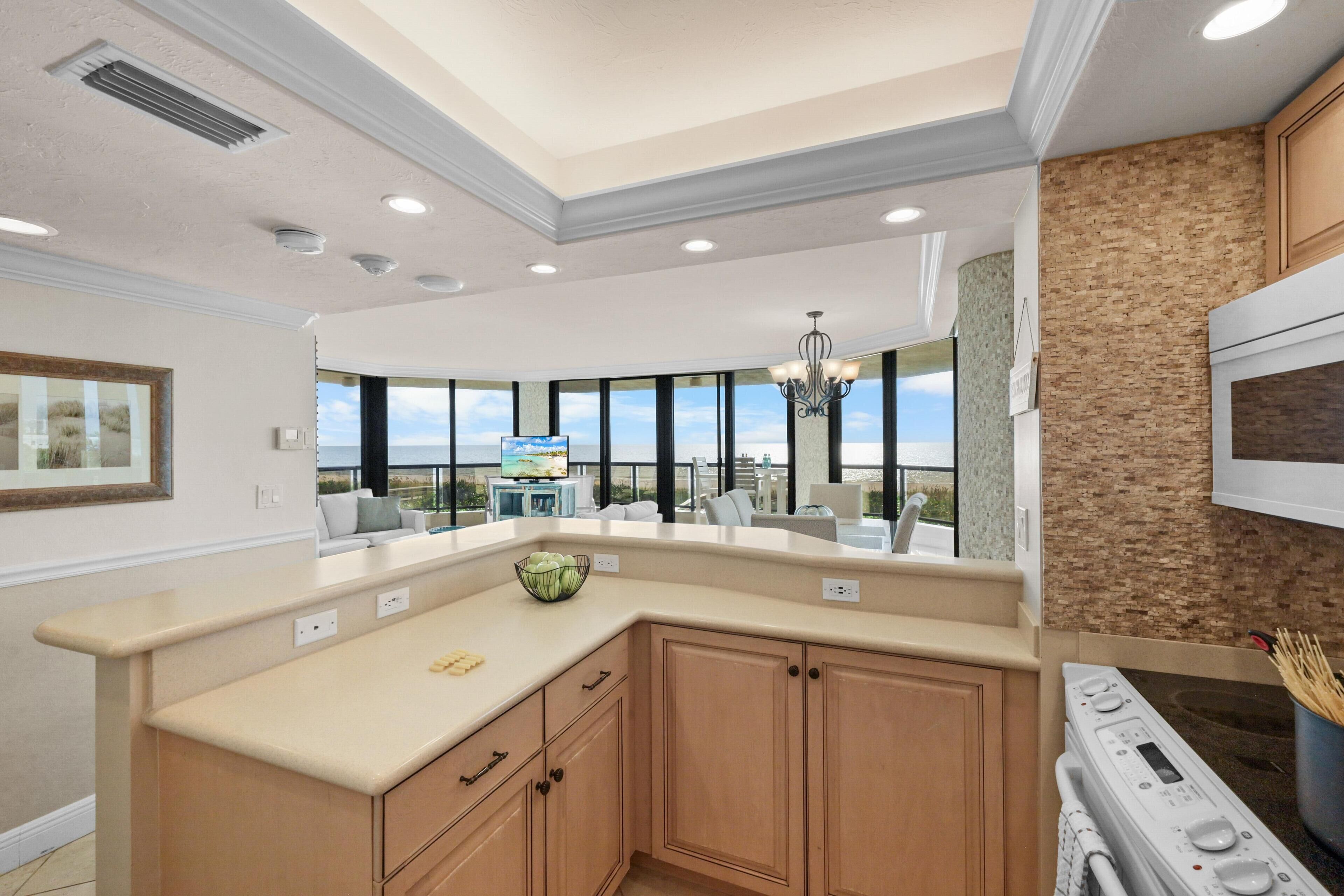 A modern kitchen with a large island, built-in oven, and a view of the outdoors.