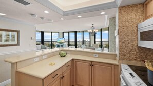 A modern kitchen with a large island, built-in oven, and a view of the outdoors.