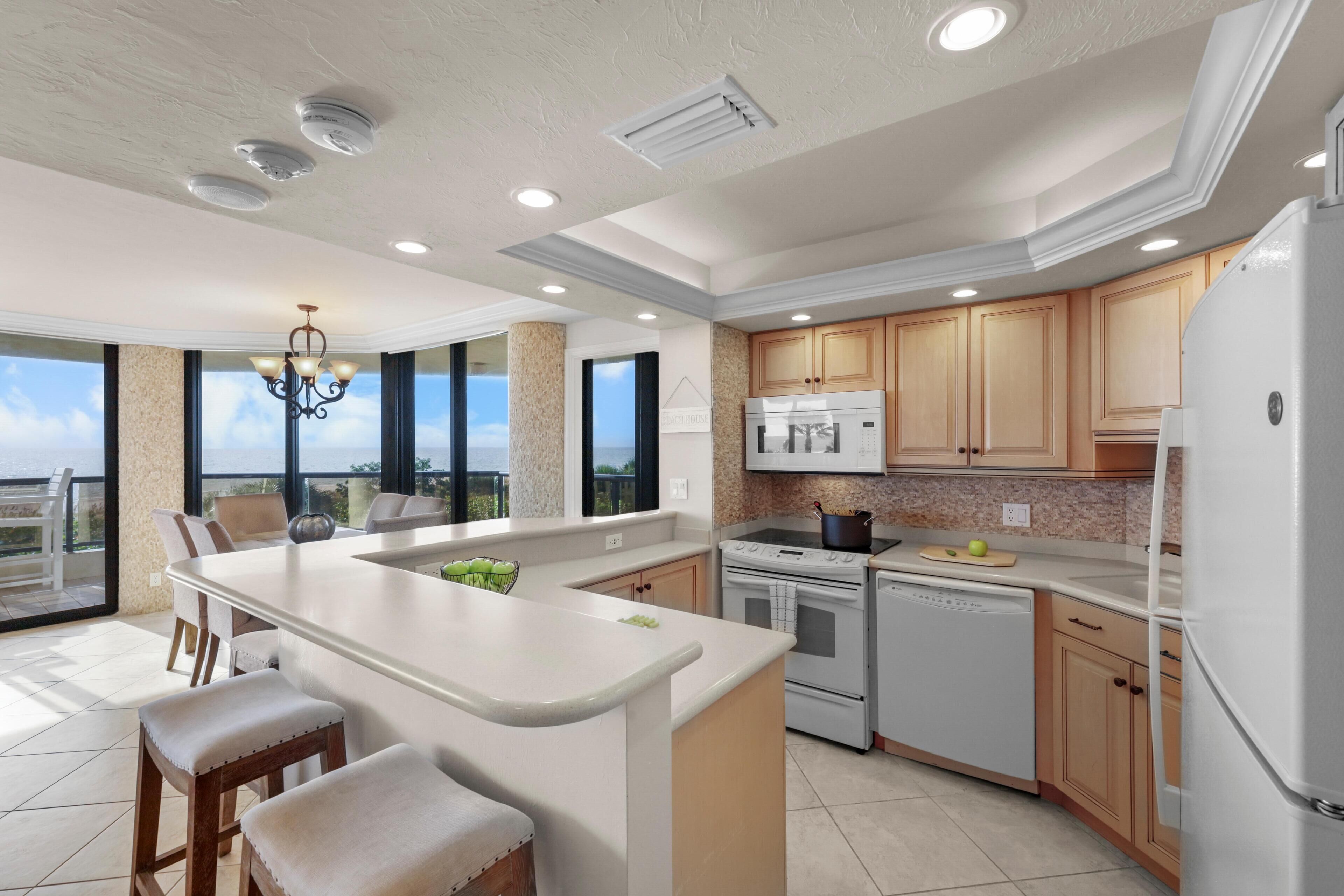A modern kitchen with a large island, built-in appliances, and a view to the outside.
