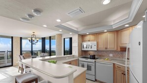 A modern kitchen with a large island, built-in appliances, and a view to the outside.