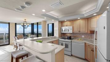 A modern kitchen with a large island, built-in appliances, and a view to the outside.