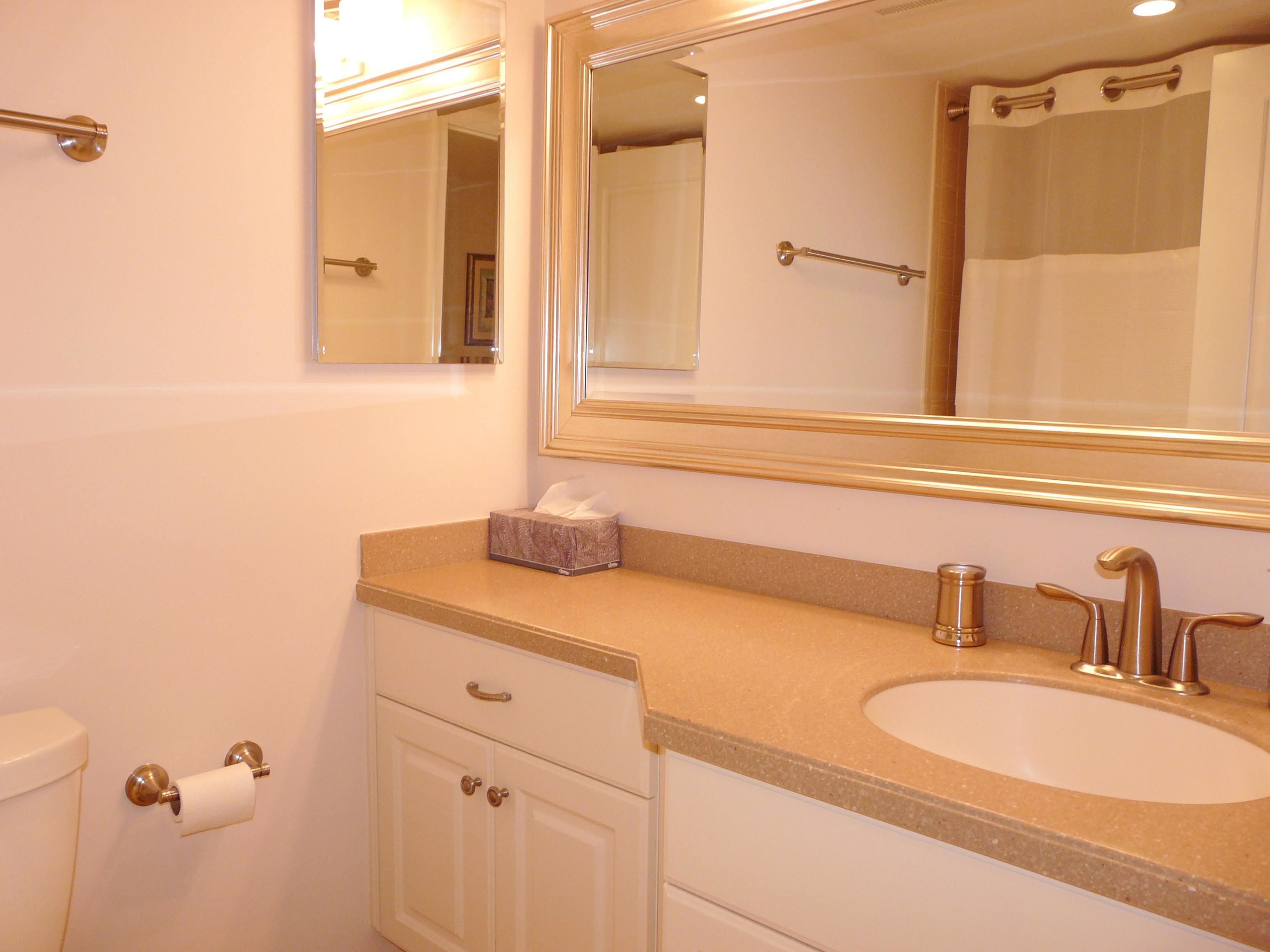 A bathroom with a large mirror, a sink, and a toilet.
