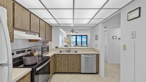 A modern kitchen with wooden cabinets, a built-in oven, a microwave, and a dishwasher. - Eye-catching Beachfront Condo With Pool and Nice Views (Marco Island)