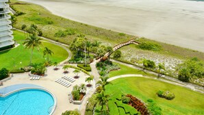 A resort with a pool, lounge chairs, and a beach view. - Eye-catching Beachfront Condo With Pool and Nice Views (Marco Island)
