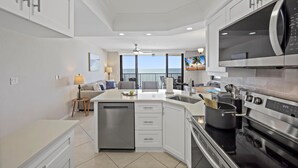 A modern kitchen with a central island, stainless steel appliances, and a view to the outside. - Inviting Beachfront Condo With Pool, spa and Views (Marco Island)