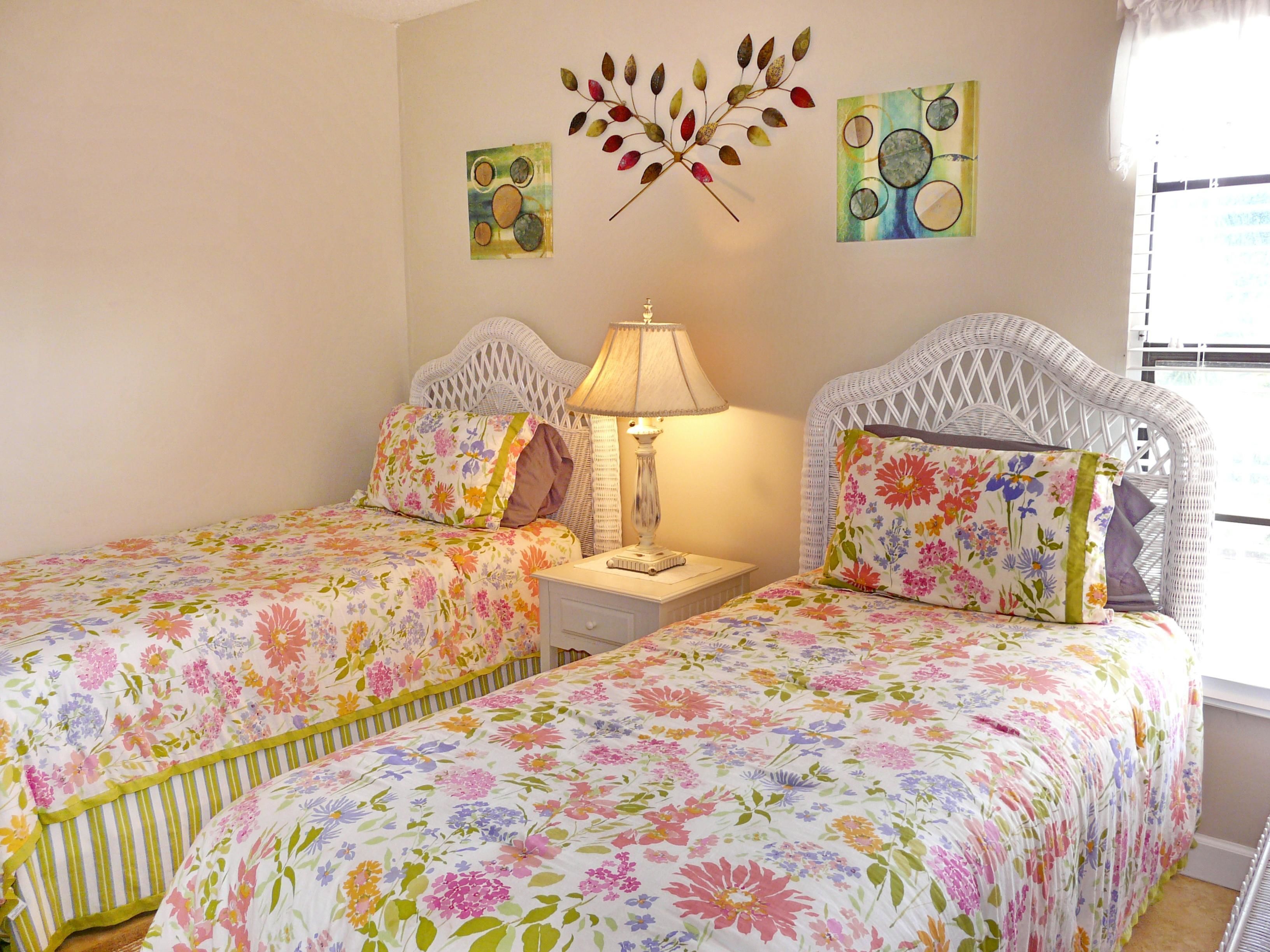 A bedroom with two beds, a nightstand, a lamp, and wall art.
