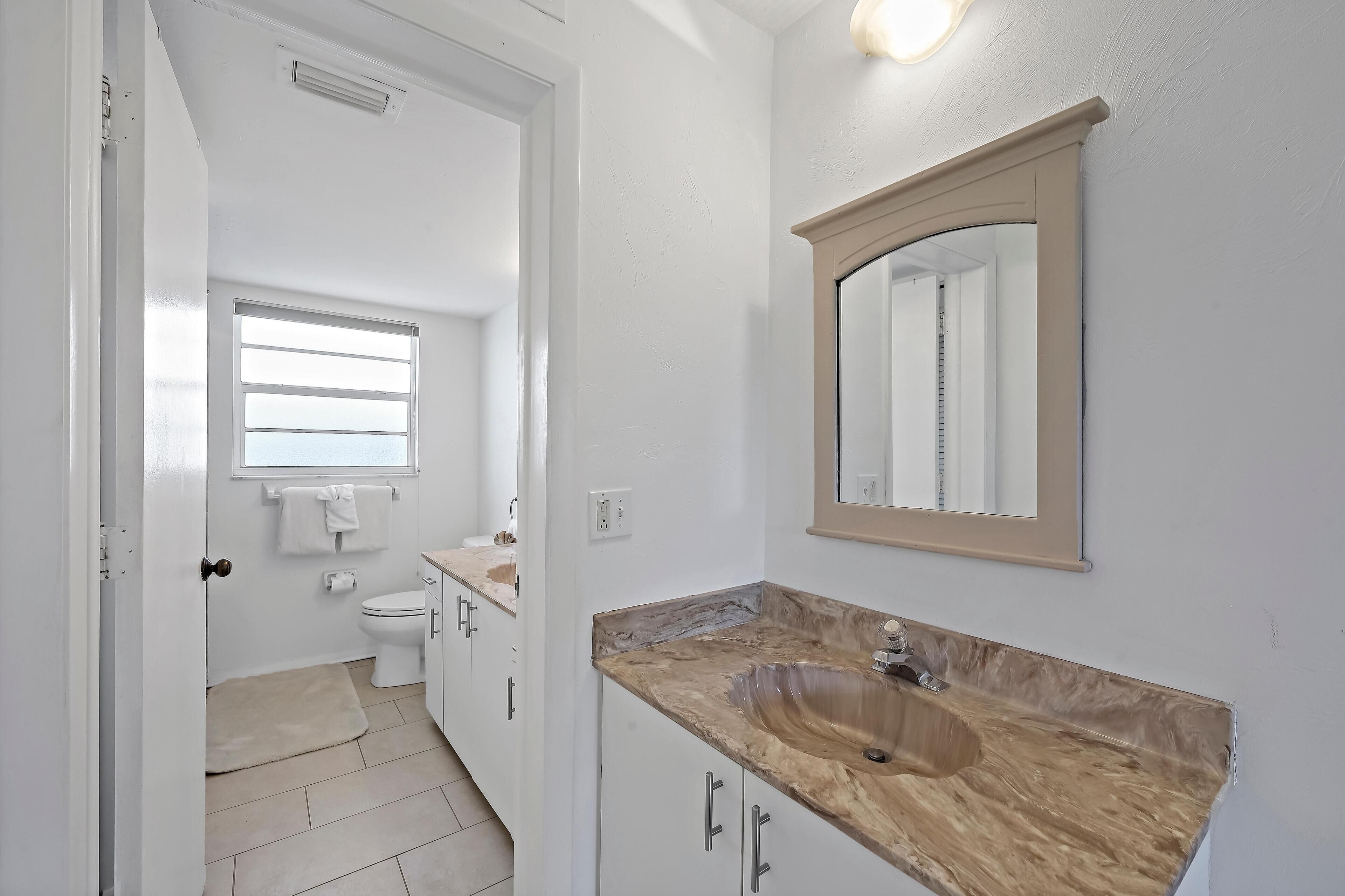 Une salle de bain avec un lavabo en marbre, des toilettes et une fenêtre.