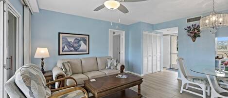 A living room with a ceiling fan, a wooden coffee table, a sofa, and a dining table with chairs.