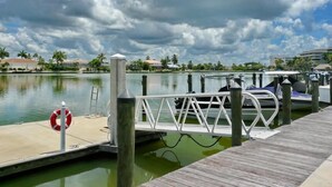 A dock with a lifebuoy, a metal railing, and a wooden walkway leading to a body of water.