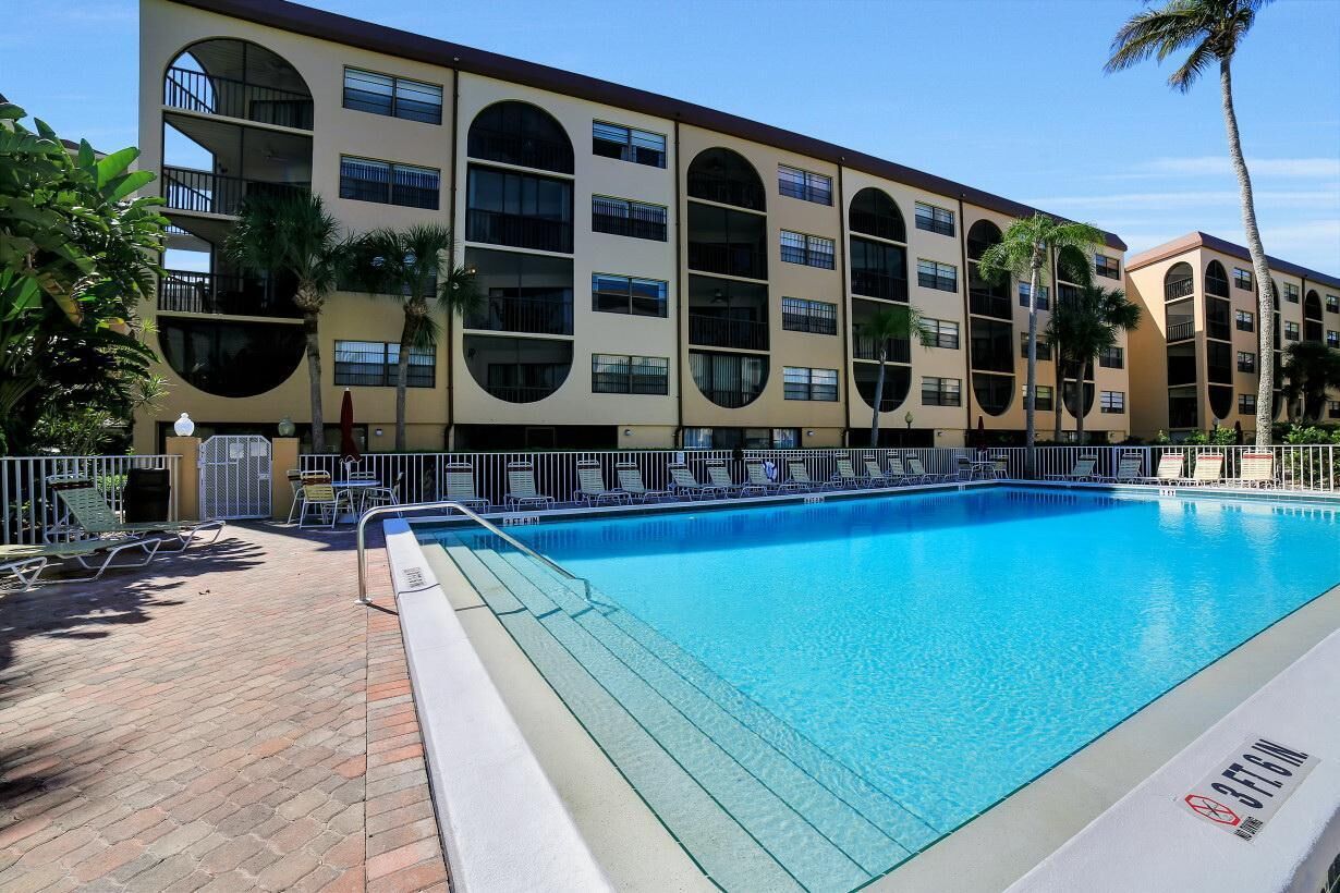 Un hôtel doté d’une grande piscine extérieure, de nombreux balcons et de palmiers.