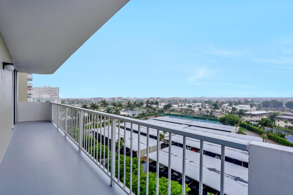 A balcony with a clear view of a parking garage and surrounding buildings.