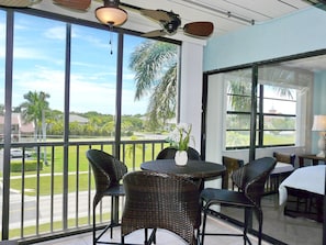 A balcony with wicker furniture and a table with a vase of flowers. - Anglers Cove D-404 (Marco Island)