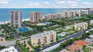 Un complejo hotelero frente al mar con varias torres, piscina y jardines bien cuidados con palmeras.