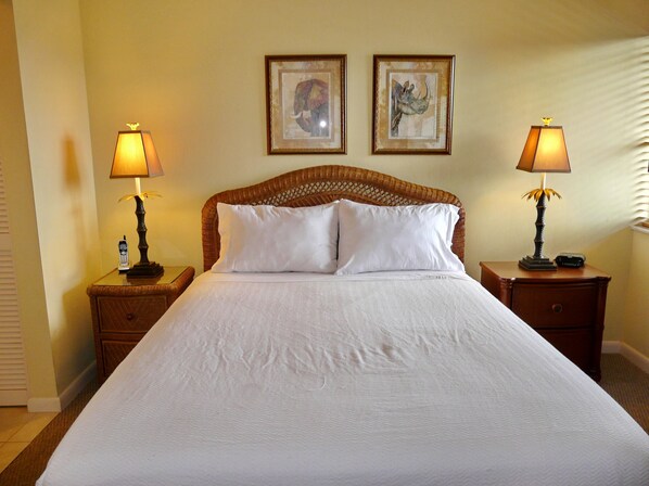 A hotel room with a large bed, two nightstands, two lamps, and two framed pictures on the wall. - Beach Club 413 (Marco Island)