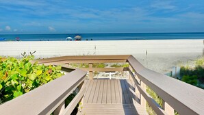 Una terraza de madera con vista a una playa y un cielo despejado.