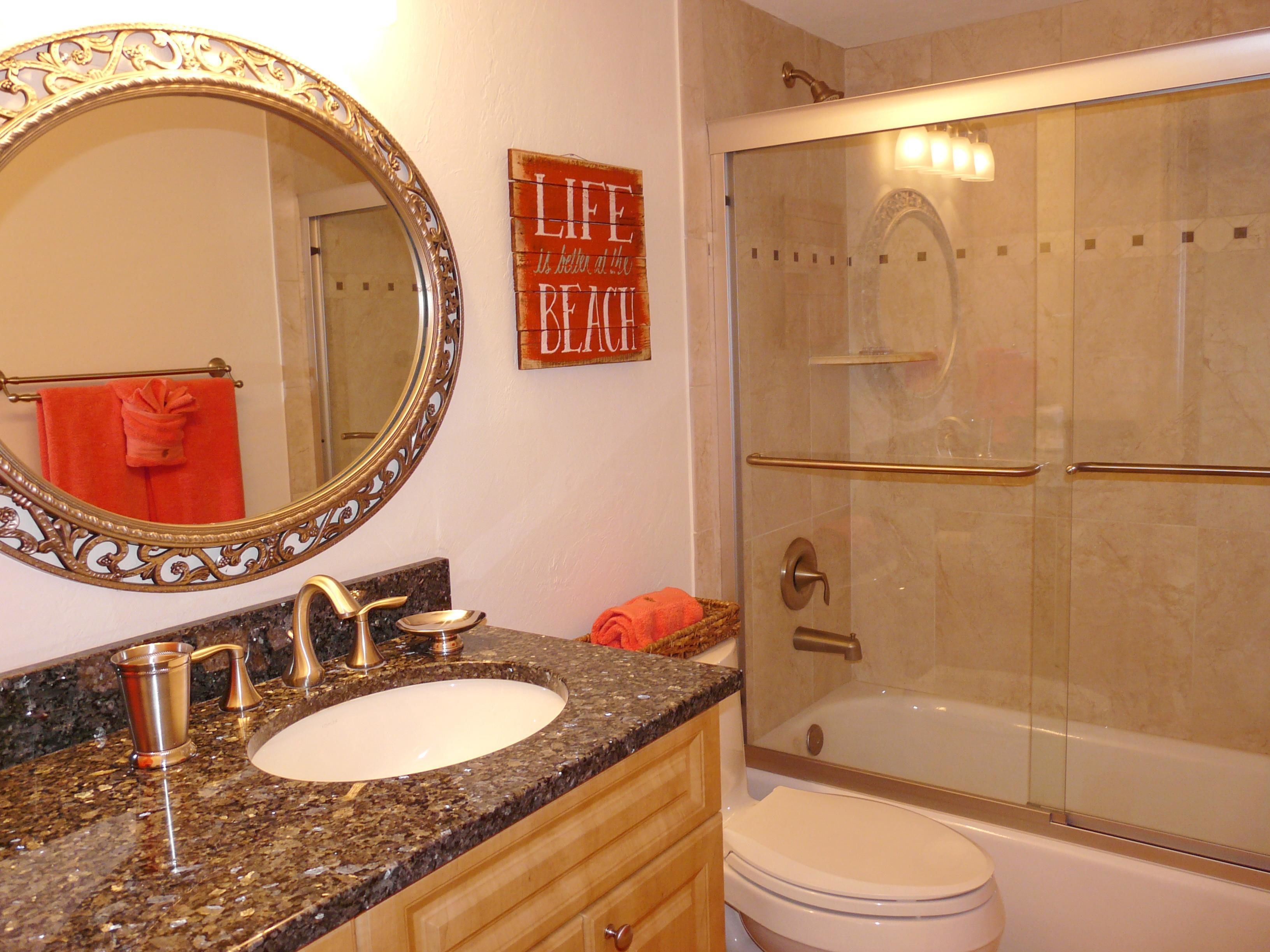 A bathroom with a marble sink, a large mirror, a glass-enclosed shower, and a toilet.