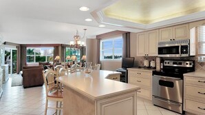 A spacious kitchen with a central island, stainless steel appliances, and a dining area with chairs and a chandelier.