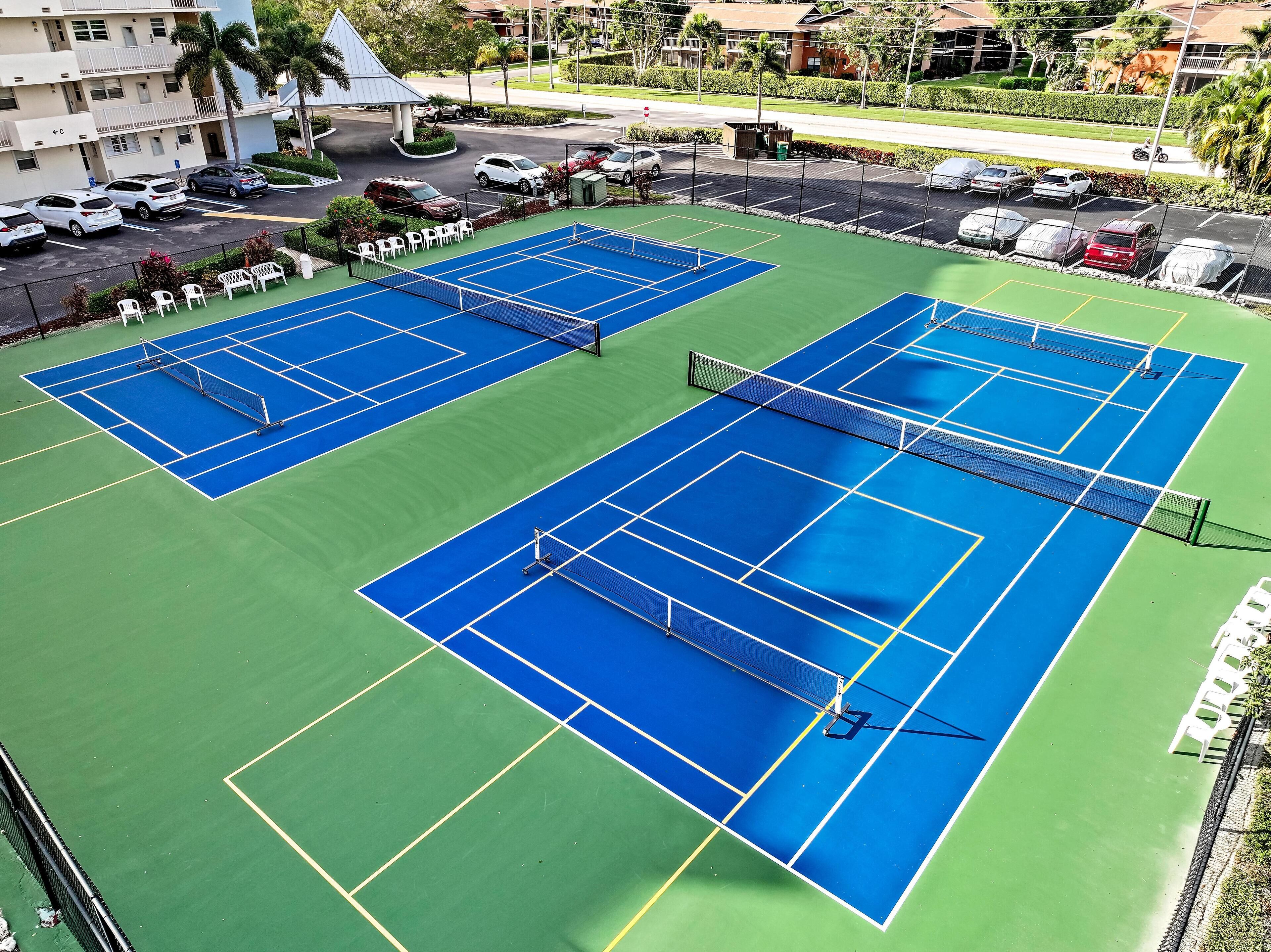 Two tennis courts with a net in the middle, surrounded by a fence.