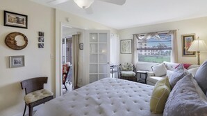 Camera da letto con un grande letto, una ventola a soffitto, una finestra con persiane e vista all'esterno.