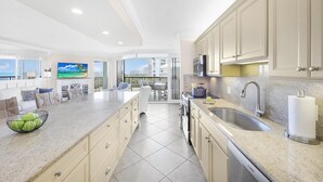 A modern kitchen with granite countertops, stainless steel appliances, and beige cabinetry. - Cozy Beachfront Getaway With Pool and spa (Marco Island)