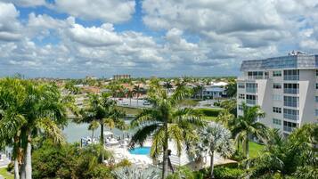 A resort with a swimming pool, palm trees, and a view of the city skyline.