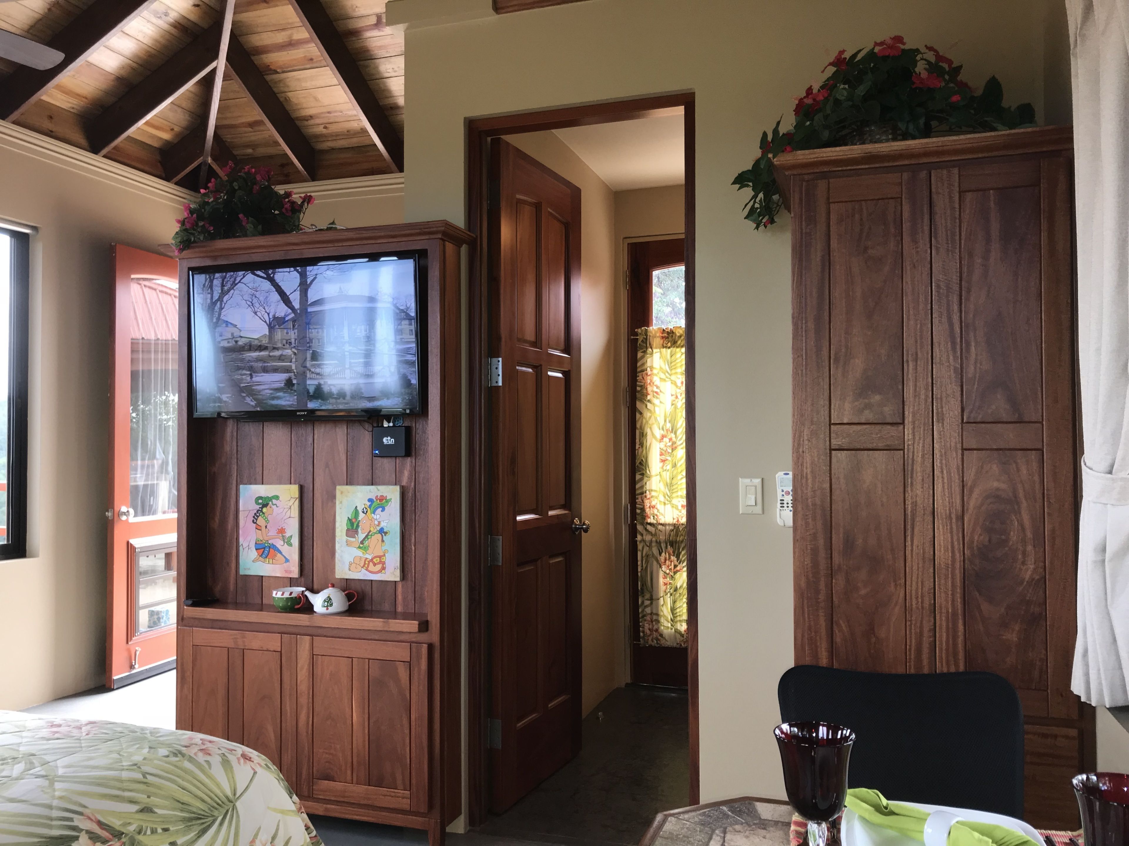 Una habitación con paneles de madera, un televisor montado en la pared y un aparador con adornos.