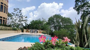 Una piscina rodeada de exuberante follaje y un edificio con balcón.