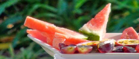 Un plato blanco con rebanadas de sandía y mitades de fruta de la pasión sobre un mantel blanco.
