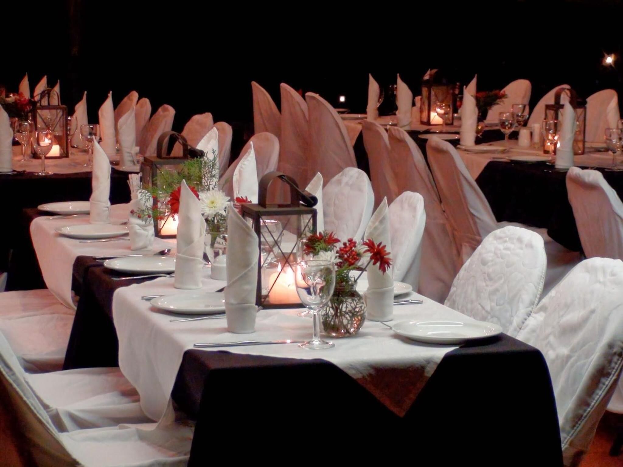 Una elegante disposición para el comedor con manteles blancos, servilletas dobladas con cuidado y una cálida iluminación de velas.