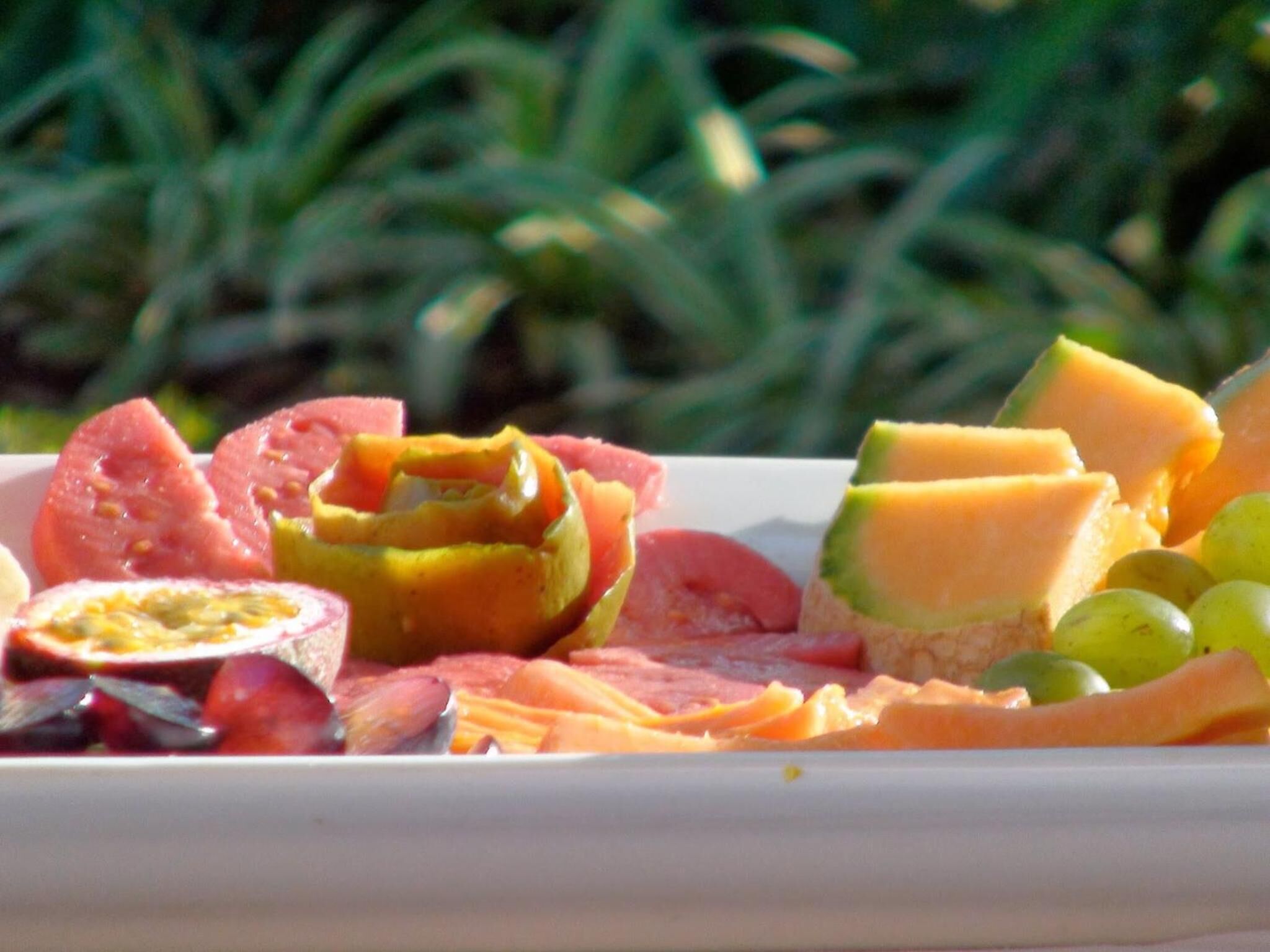 A fruit platter with various fruits including melon, grapes, and tomatoes.