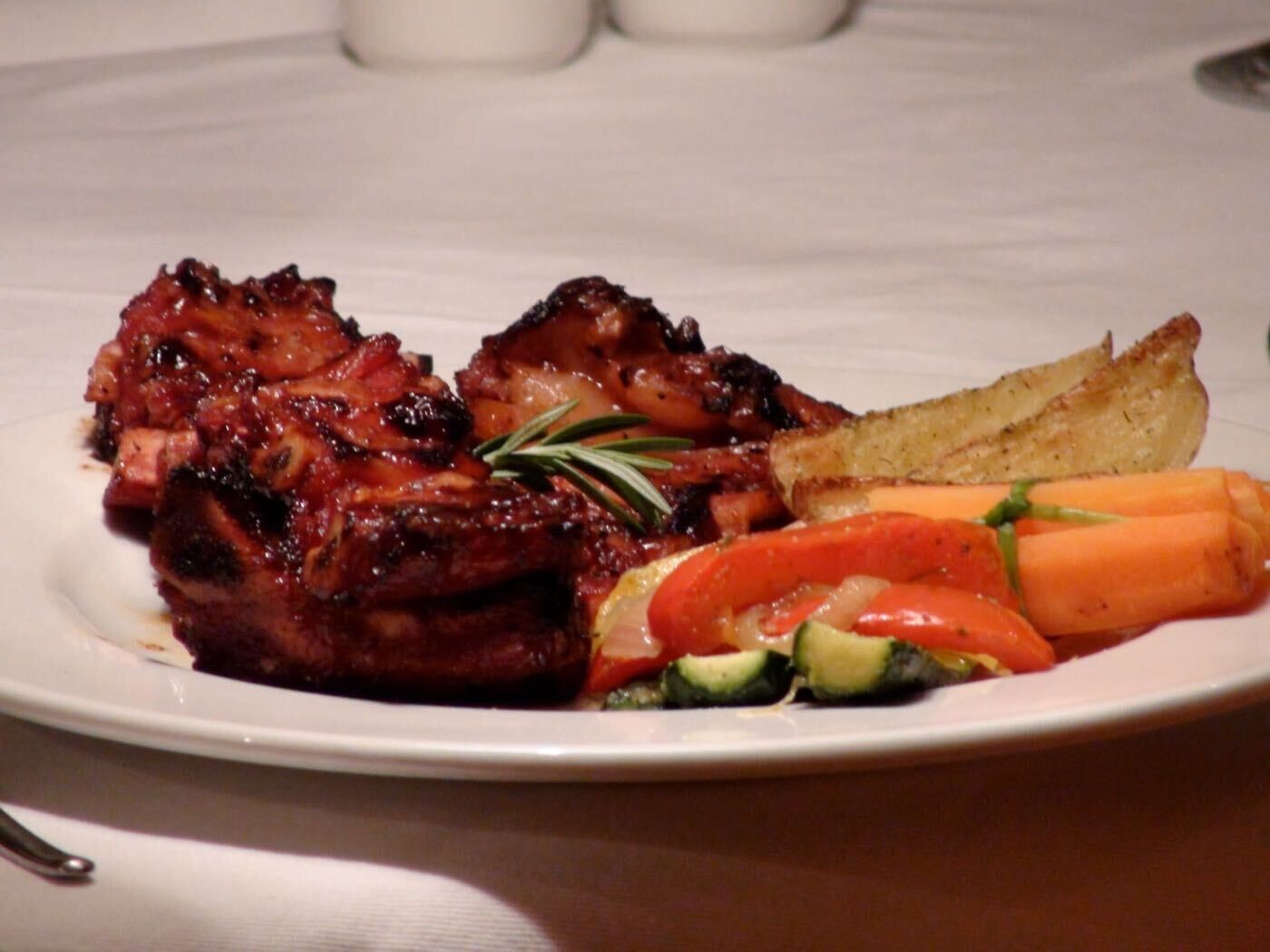 A plate with grilled meat, roasted potatoes, and mixed vegetables.