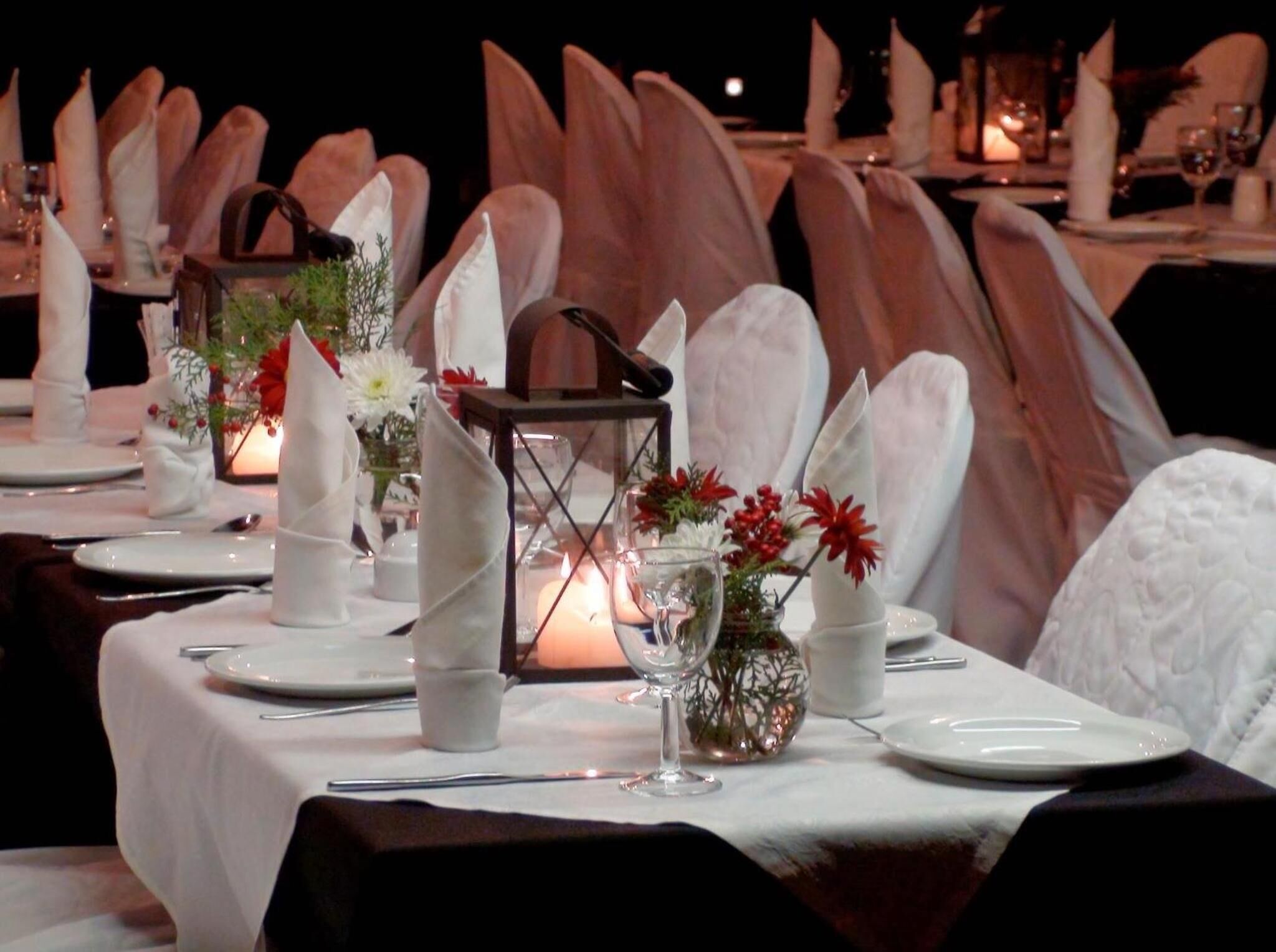 A table set for a formal dinner with white tablecloths, plates, cutlery, and decorative elements like candles and flowers.
