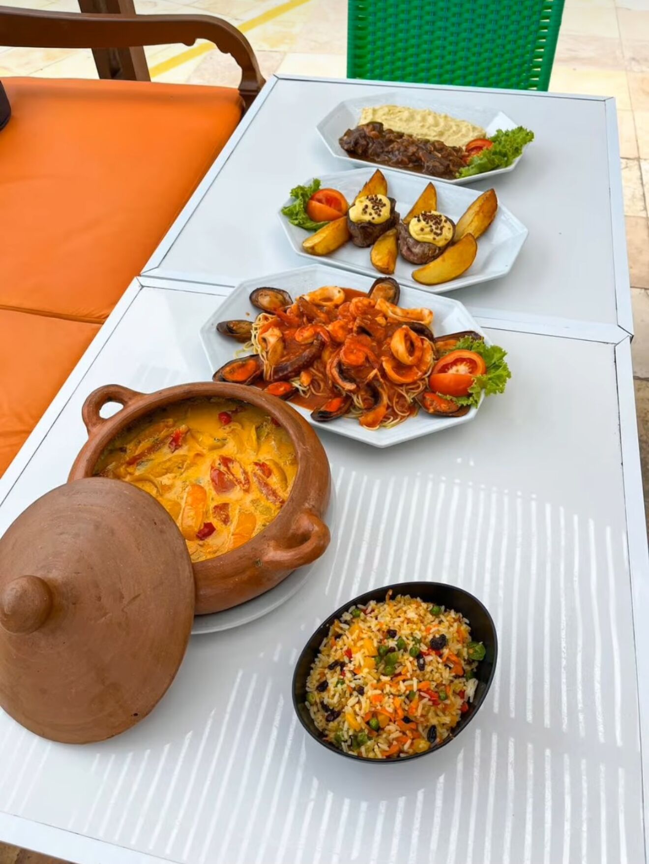 A table with a variety of dishes including seafood, rice, and a stew, suggesting a dining setup.