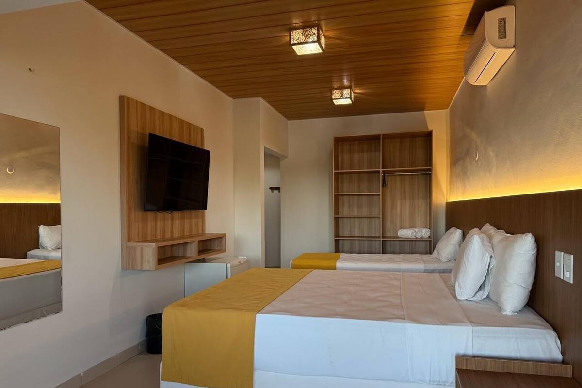 A modern hotel room with a large bed, a TV mounted on the wall, and a built-in wardrobe.