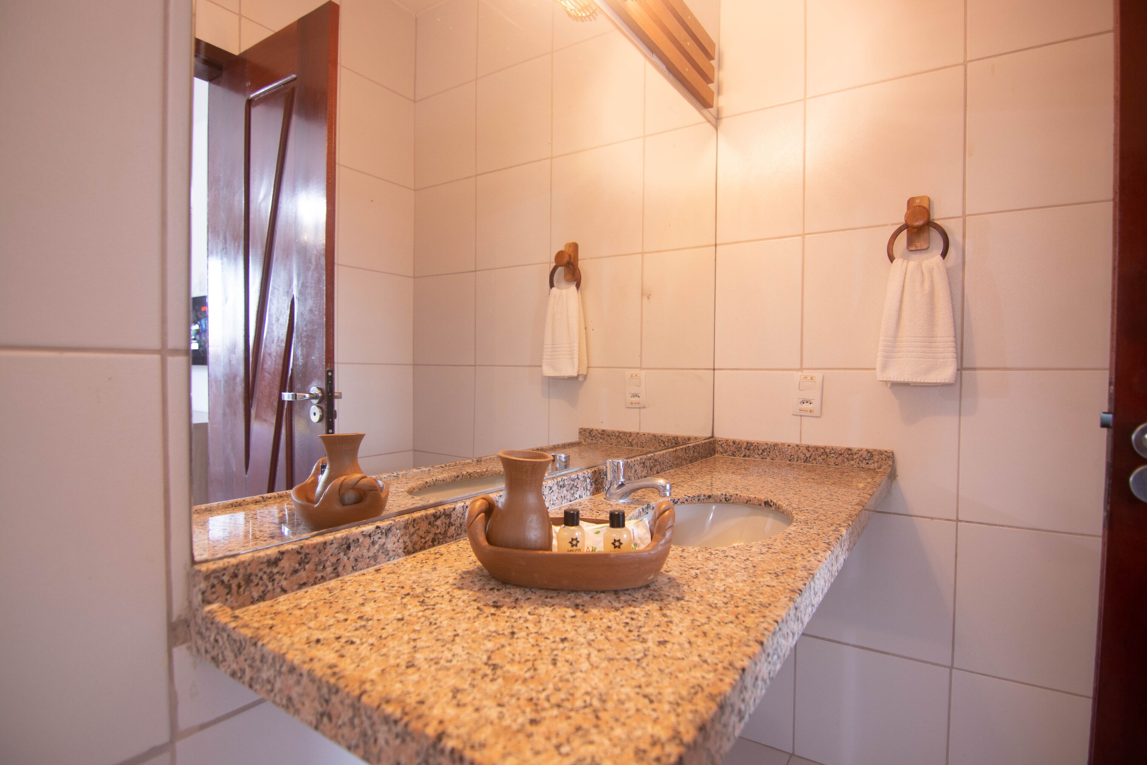 Un baño con encimera de granito, un lavabo, un espejo y dos toallas colgadas en ganchos.