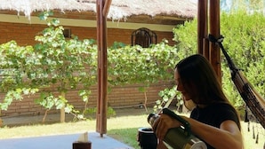 A person pouring a drink into a mug at a wooden table under a thatched roof structure. - La Vita e Bella  Cabanas en San Rafael (San Rafael)