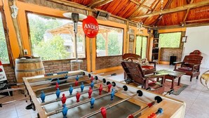 A room with a foosball table, wooden furniture, and large windows. - La Vita e Bella  Cabanas en San Rafael (San Rafael)