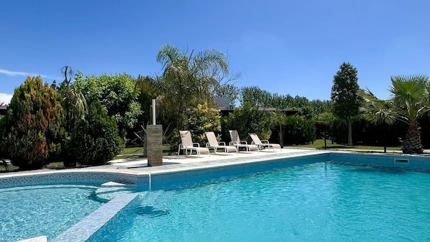 A clear blue swimming pool with white lounge chairs and a stone structure in the background. - La Vita e Bella  Cabanas en San Rafael (San Rafael)