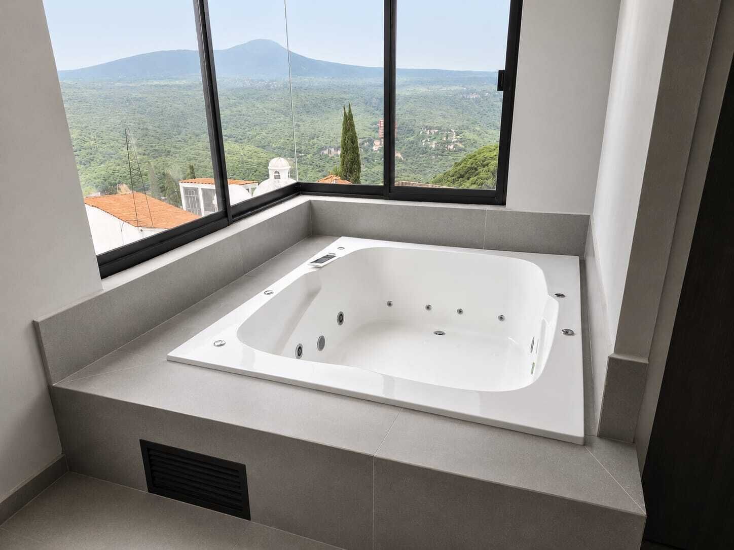 Un bagno moderno con una vasca da bagno indipendente, ampie finestre e vista su un paesaggio montuoso.