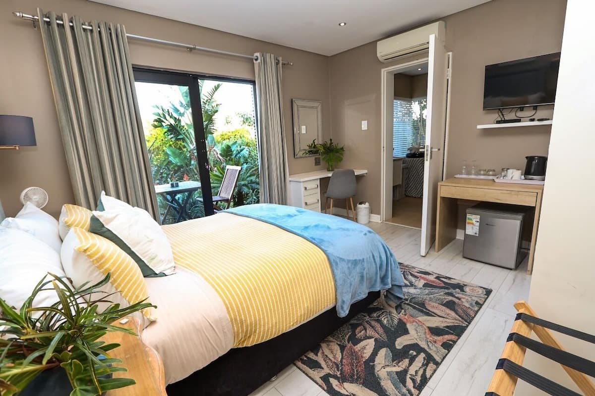 A bedroom with a bed, a desk, a television, and a small refrigerator.