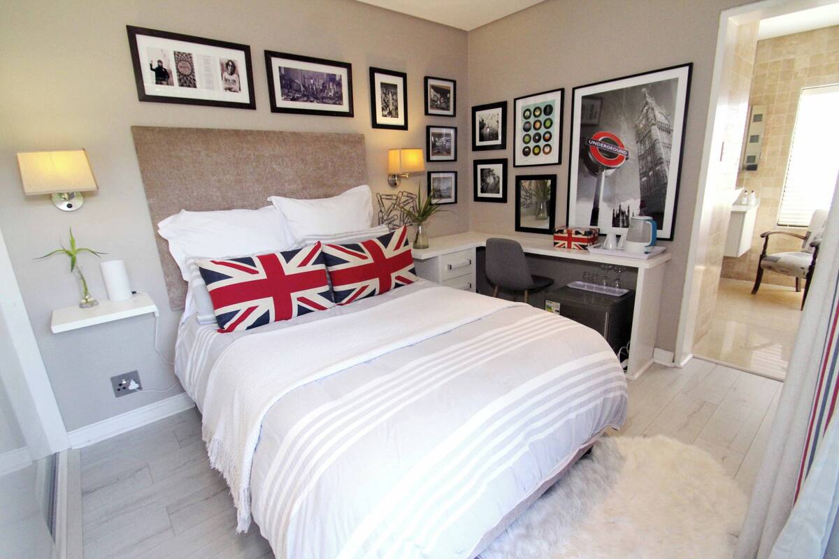 A neatly arranged bedroom with a bed, bedside tables, a desk, and a chair.