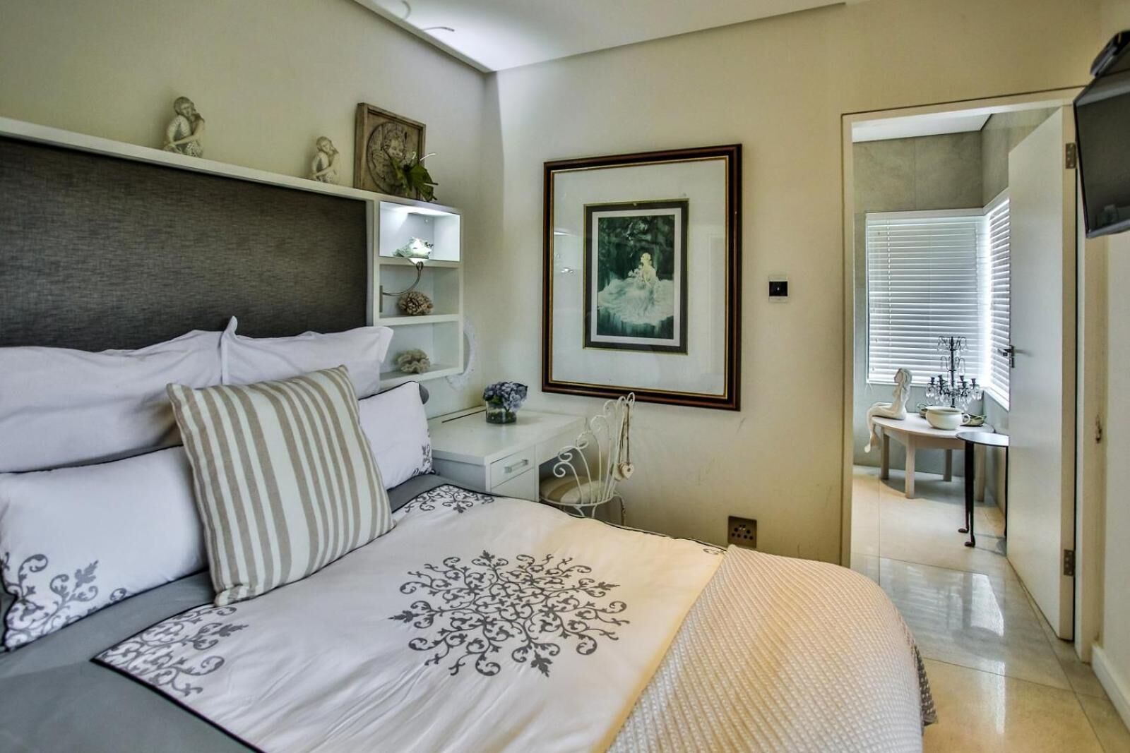 A bedroom with a bed, bedside tables, a dresser, and a framed picture on the wall.