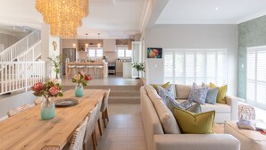 A spacious living area with a wooden dining table, a sofa set, and a chandelier. - Bentley's Guesthouse (Cape Town)