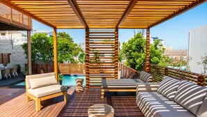 A wooden deck with a pool, outdoor seating, and a pergola. - Bentley's Guesthouse (Cape Town)