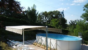 An outdoor swimming pool with a covered area and lounge chairs.