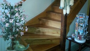 A wooden staircase with a hanging puppet and a potted plant.