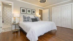 Une chambre à coucher avec un grand lit, une table de chevet, un ventilateur de plafond et une porte.